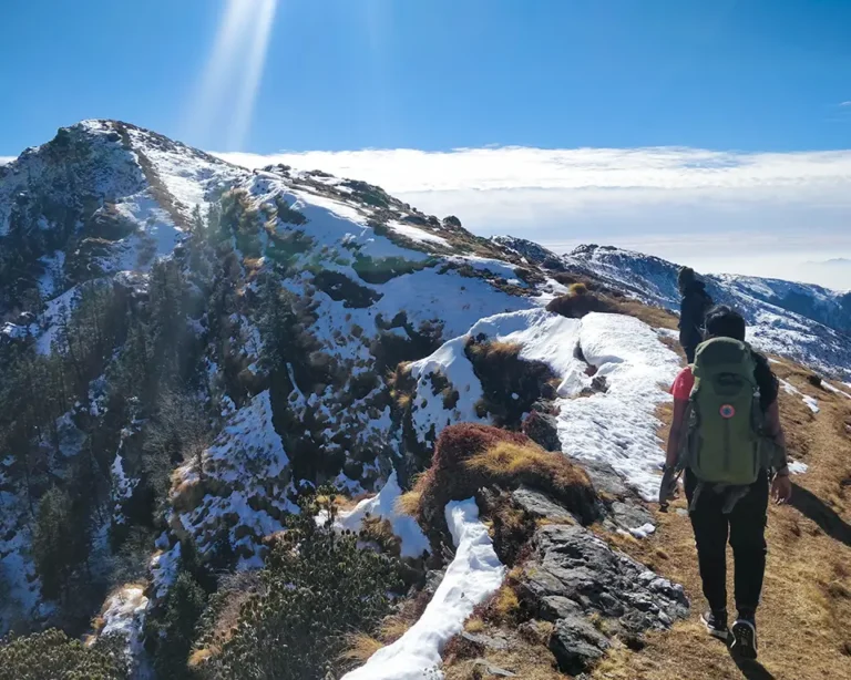 Trekkers climbing a snowy ridge under a bright winter sky